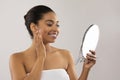 Happy attractive african american woman applying face cream and smiling Royalty Free Stock Photo