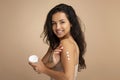 Happy attractive brunette woman applying body cream on shoulder Royalty Free Stock Photo