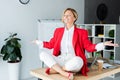 happy attractive businesswoman meditating in lotus pose on table