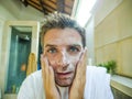 Happy and attractive Caucasian man smiling fresh at home bathroom washing his face with exfoliant soap looking at himself in toile Royalty Free Stock Photo