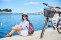 Happy attractive girl in sunglasses and with backpack riding a bike along stony sidewalk Royalty Free Stock Photo