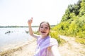 Happy attractive girl taking selfie picture with smart mobile phone device at the lake side. Delightful beautiful young Royalty Free Stock Photo