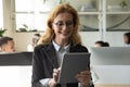 Happy attractive mature businesswoman using tablet and getting good news. Royalty Free Stock Photo