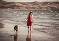 Happy attractive mature woman with her pet walking on friendly dog beach at sunset Royalty Free Stock Photo
