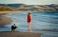 Happy attractive mature woman with her pet walking on friendly dog beach at sunset Royalty Free Stock Photo