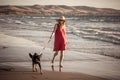 Happy attractive mature woman with her pet walking on friendly dog beach at sunset Royalty Free Stock Photo