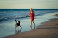 Happy attractive mature woman with her pet walking on friendly dog beach at sunset Royalty Free Stock Photo