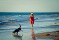 Happy attractive mature woman with her pet walking on friendly dog beach at sunset Royalty Free Stock Photo