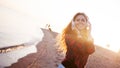 Happy attractive red-haired girl is enjoying favorite music on walk. Beautiful young woman in shirt uses headphones Royalty Free Stock Photo