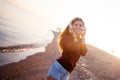 Happy attractive red-haired girl is enjoying favorite music on walk. Beautiful young woman in shirt uses headphones Royalty Free Stock Photo