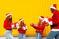 Happy attractive rejoicing girlfriends in santa claus hats celebrate new year with christmas gifts, outdoors Royalty Free Stock Photo