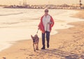 Happy attractive senior woman with her german shepard dog walking on the beach at autumn sunset Royalty Free Stock Photo