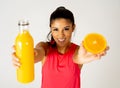 Happy attractive sporty woman holding glass of fresh orange juice and orange fruit Royalty Free Stock Photo