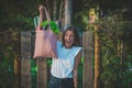 Happy attractive vegan woman holding reusable grocery bag full of vegetables