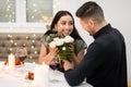 Happy attractive woman holding flowers, looking at her handsome boyfriend