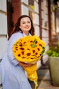 attractive woman with huge bouquet of decorative sunflowers at the city