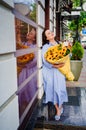 attractive woman with huge bouquet of decorative sunflowers at the city