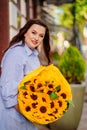 attractive woman with huge bouquet of decorative sunflowers at the city