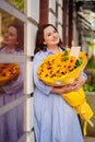 attractive woman with huge bouquet of decorative sunflowers at the city