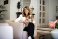 A middle-aged woman sittingnin an armchair at home with her puppy on her lap Royalty Free Stock Photo