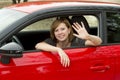 Happy attractive woman sitting at driver seat smiling cheerful and proud waving hello from new car