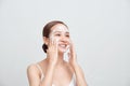 Happy attractive young Asian woman applying foaming cleanser on her face over white background