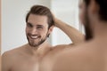 Happy attractive young guy touching smooth silky hair