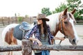 Happy attractive young woman cowgirl with horse on ranch Royalty Free Stock Photo