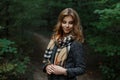 Happy attractive young woman in a fashionable gray coat with a stylish checkered scarf is standing on a path in the forest Royalty Free Stock Photo