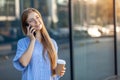 Happy attractive young woman talking on smartphone, holding take away coffee cup Royalty Free Stock Photo