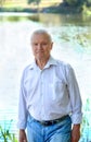 Happy ÃÂaucasian older mature gray-haired man 60 plus in white shirt and blue jeans by the lake. Retired lifestyle. Rest and