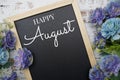 Happy August text on background decorated with flower bouquet on wooden background