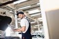 Happy auto mechanic holding laptop at