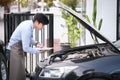 Happy auto repairman writing notes while checklist for repair machine a car in auto repair shop