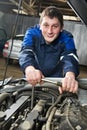 Happy automotive mechanic at work with wrench