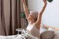 Happy awakened aged woman stretching after night sleeping Royalty Free Stock Photo