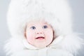 Happy baby in big fur hat and white snow jacket Royalty Free Stock Photo