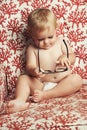 Happy baby, blonde boy and playing with glasses on sofa in growth, youth or development in living room at home. Cute