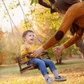 Happy baby boy having fun on a swing ride at a garden a autumn day Royalty Free Stock Photo