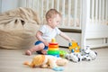 Happy baby boy playing with toys on floor at bedroom Royalty Free Stock Photo