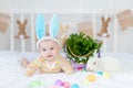 Happy baby boy with rabbit ears on his head lying with a rabbit on the bed with Easter eggs, cute funny smiling little baby. The Royalty Free Stock Photo