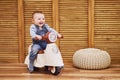 Happy baby boy rides a plastic children motorcycle in the playroom. A