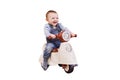 Happy baby boy rides a plastic children motorcycle in the playroom, iso