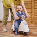 Happy baby boy rides a plastic children motorcycle in the playroom. A
