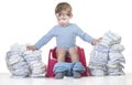 Happy baby boy sitting on chamber pot tearing down diaper piles