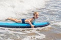 Happy baby boy - young surfer ride on surfboard with fun on sea