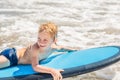 Happy baby boy - young surfer ride on surfboard with fun on sea