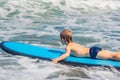 Happy baby boy - young surfer ride on surfboard with fun on sea