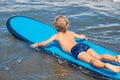 Happy baby boy - young surfer ride on surfboard with fun on sea waves. Active family lifestyle, kids outdoor water sport Royalty Free Stock Photo