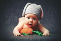 Happy baby child in costume a rabbit bunny with carrot on a grey